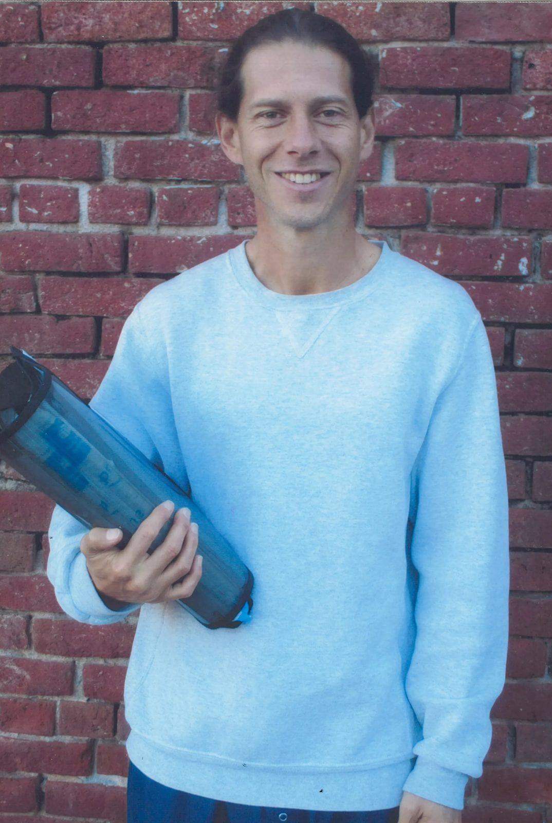 Kelton O'Connor standing before a brick wall, smiling