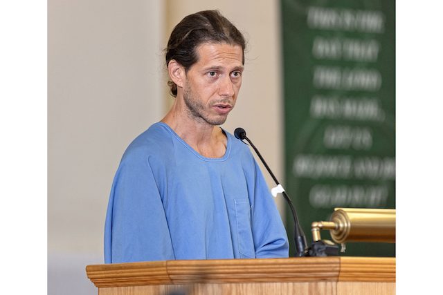 Kelton speaking at a podium at San Quentin